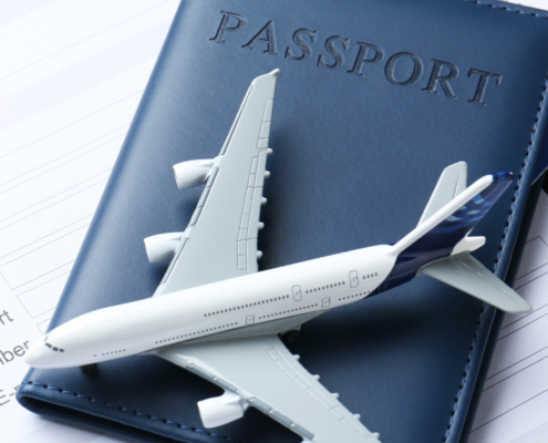 White model airplane resting on a blue passport, symbolizing international travel and flight preparation.